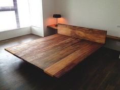 a bed sitting in the middle of a room next to a wooden floor and window