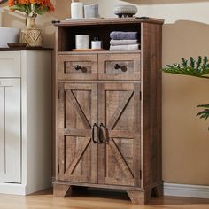 a wooden cabinet with doors and drawers in the corner next to a potted plant