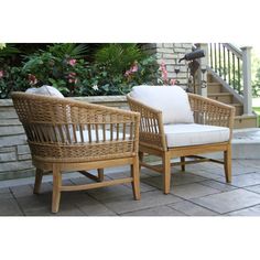 two wicker chairs sitting next to each other on a stone patio with flowers in the background