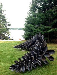 a large metal sculpture sitting on top of a lush green field next to a lake