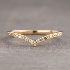 a gold wedding band with white diamonds on the side, sitting on a gray surface