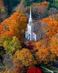 an aerial view of a church surrounded by trees with fall foliage in the foreground