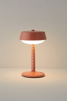 an orange table lamp sitting on top of a white surface