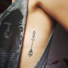 the back of a woman's upper arm with an arrow tattoo on it