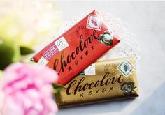 two chocolate bars sitting next to each other on a doily with flowers in the background