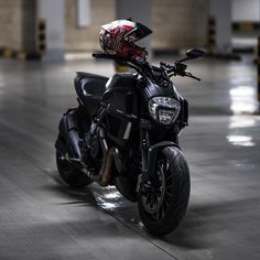 a black motorcycle parked in a parking garage with a helmet on the back end of it