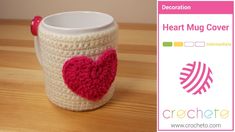 a crocheted cup with a red heart on it and a sticker next to it