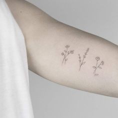 a woman's arm with three small flowers on the left side of her arm