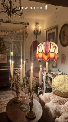 a living room filled with furniture and a chandelier next to a table topped with candles