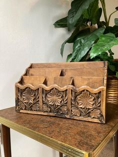 a wooden box sitting on top of a table next to a potted plant