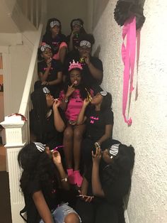 a group of women dressed in black and pink sitting on the stairs with each other