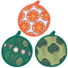 three oranges and broccoli designs on two round pot holders, one in green