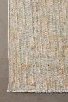 an old rug with fringes on the bottom, and a small white object in the middle