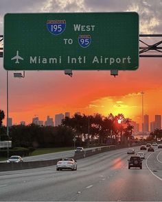 cars driving down the highway in front of a city skyline at sunset, with an interstate sign above it