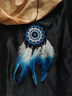 a blue and white dream catcher sitting on top of a black cloth