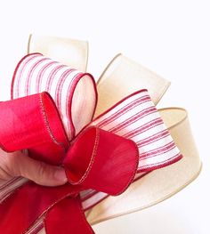 a hand holding a red and white ribbon