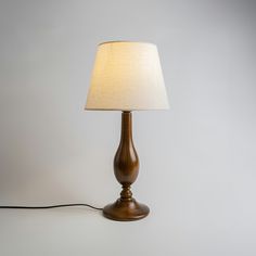 a wooden lamp with a white shade on the base and a cord attached to it