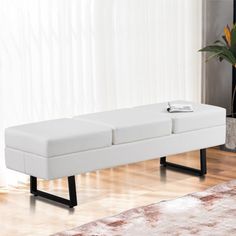 a white bench sitting on top of a hard wood floor next to a potted plant