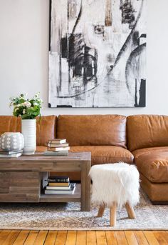 a living room with brown leather couches and a coffee table in front of a painting