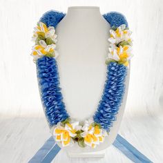 a white and blue necklace with yellow flowers on the front is sitting on a mannequin