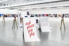 an art gallery with several large white signs and wooden poles in the middle of it