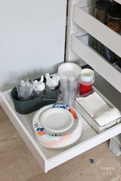 an open drawer with plates and cups on it