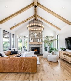 a large living room with wood flooring and a stone fireplace in the center surrounded by windows