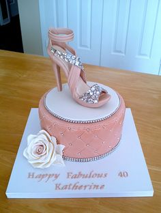 a birthday cake with a high heeled shoe and rose on the top, sitting on a table