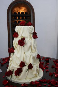 a wedding cake with red roses on the table