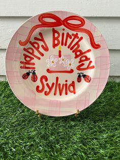 a birthday plate with ladybugs on it sitting in the grass next to a house