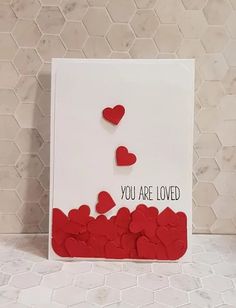 there is a card with hearts on it and the words you are loved written in red