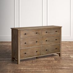 a wooden dresser sitting on top of a hard wood floor next to a white wall