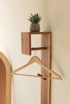 a wooden coat hanger with a potted plant on it