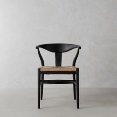 a black chair with a woven seat and backrest, against a white wall background