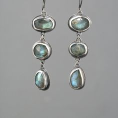 "These eye catching dangle earrings feature a row of three natural rose cut labradorite stones. They are a lovely soft grey with fascinating flashes of green and blue. They are lovingly set in handmade sterling silver bezel settings with sterling french ear wire. The silver has an oxidized finish with areas of high shine to create contrast.  The earrings measure 2 1/2\" from top to bottom." Labradorite Earrings, Dope Jewelry, Funky Jewelry, Jewelry Lookbook, Gem Stones, Stone Work, Jewelry Inspo, Dream Jewelry, Pretty Jewellery