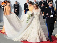 the bride and groom are walking down the red carpet at their wedding ceremony in uniform