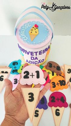 a hand is holding an ice cream cone with numbers on it and two cones in the middle