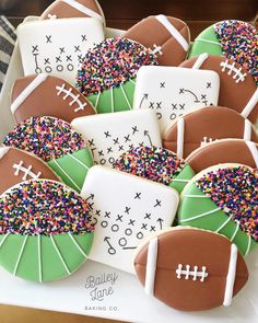 decorated cookies with footballs and sprinkles are on a platter, ready to be eaten