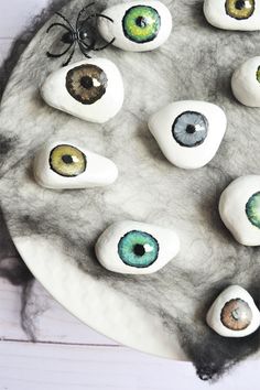 some fake rocks with eyes painted on them sitting on a white plate next to a spider