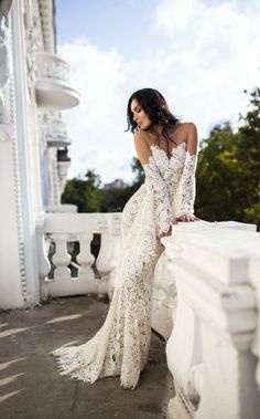 a woman in a white dress leaning on a wall