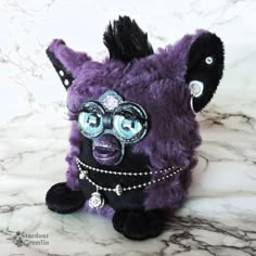 a purple and black stuffed animal with glasses on it's head sitting on a marble surface