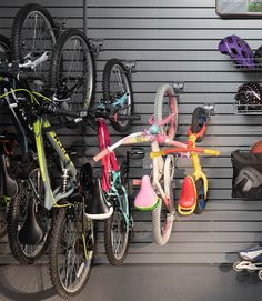 several bicycles are parked in front of a wall mounted bike rack with helmets on it