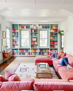 a living room filled with pink couches and bookshelves