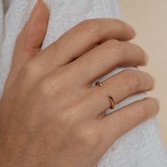 a woman's hand with a gold ring on her left hand and a white towel in the background