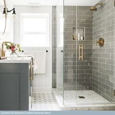 a bathroom with gray tile and gold fixtures