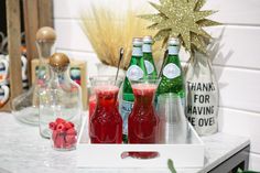 three bottles and two glasses on a table with candy canes in front of them