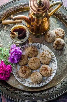 some food is sitting on a plate next to a tea pot and flowers with a copper kettle in the background