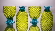 four green glass vases sitting next to each other