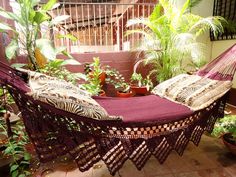 a purple hammock sitting on top of a brick floor next to potted plants