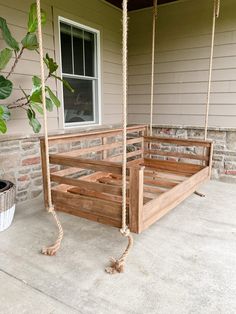 a porch swing made out of wooden pallets and roped together with a potted plant in the background